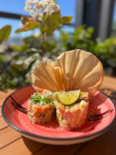 Sushi sur une assiette rouge, décoré de lime et d'une feuille de crudité.